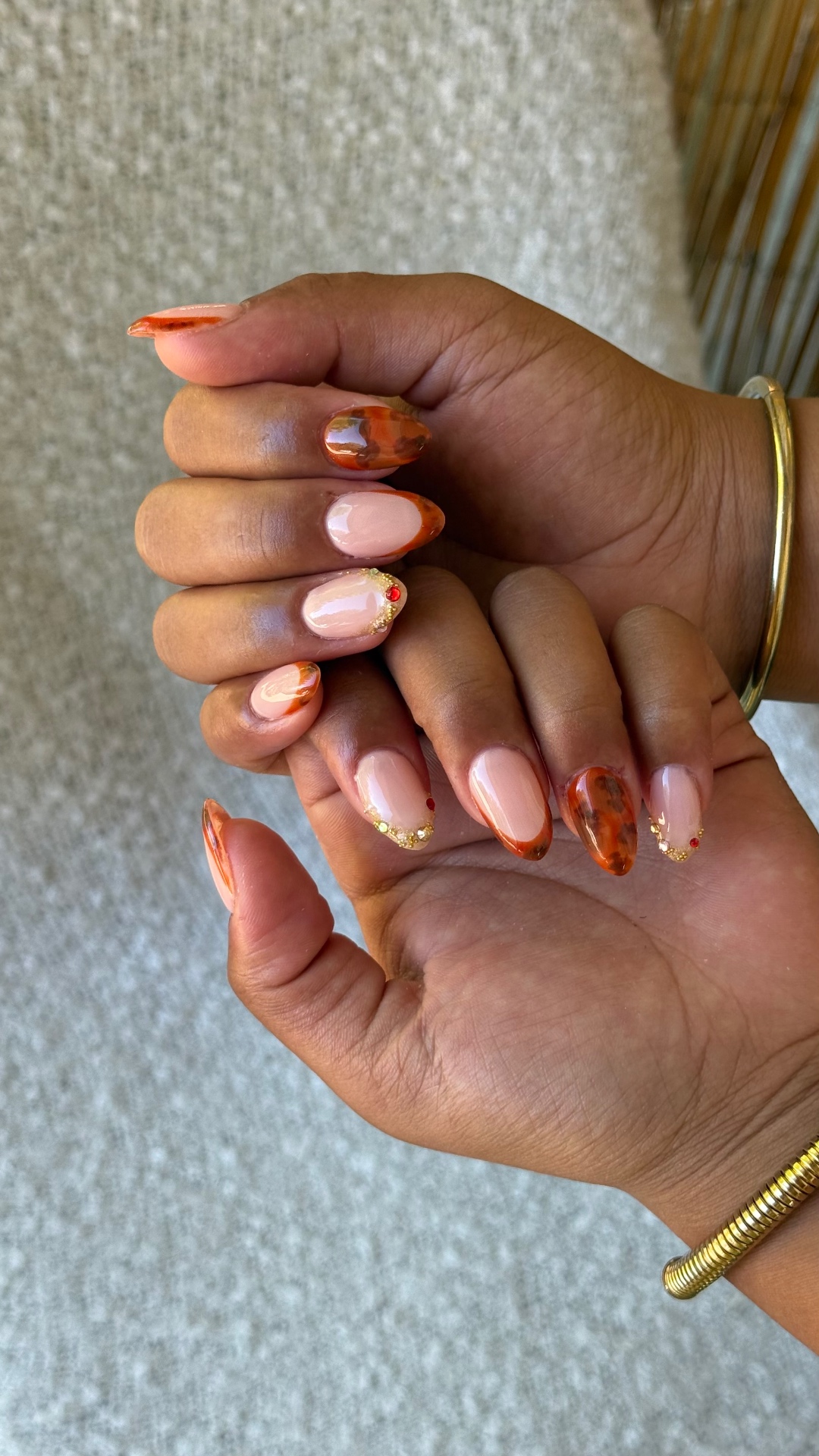 Ongles amande nude, marbrage terracotta et strass dorés